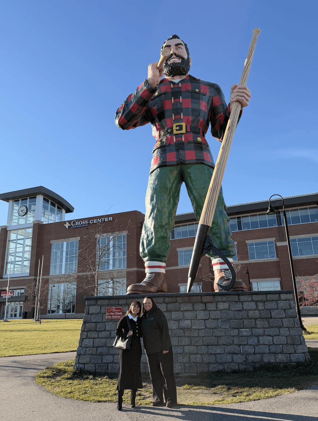 Two women posing in front of the giant Paul Bunyan statue in Bangor, Maine.